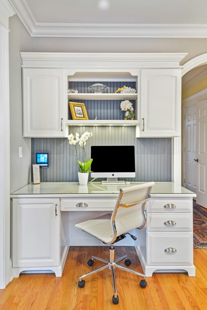 computer desk with built in cabinets and open shelving holding decorative items